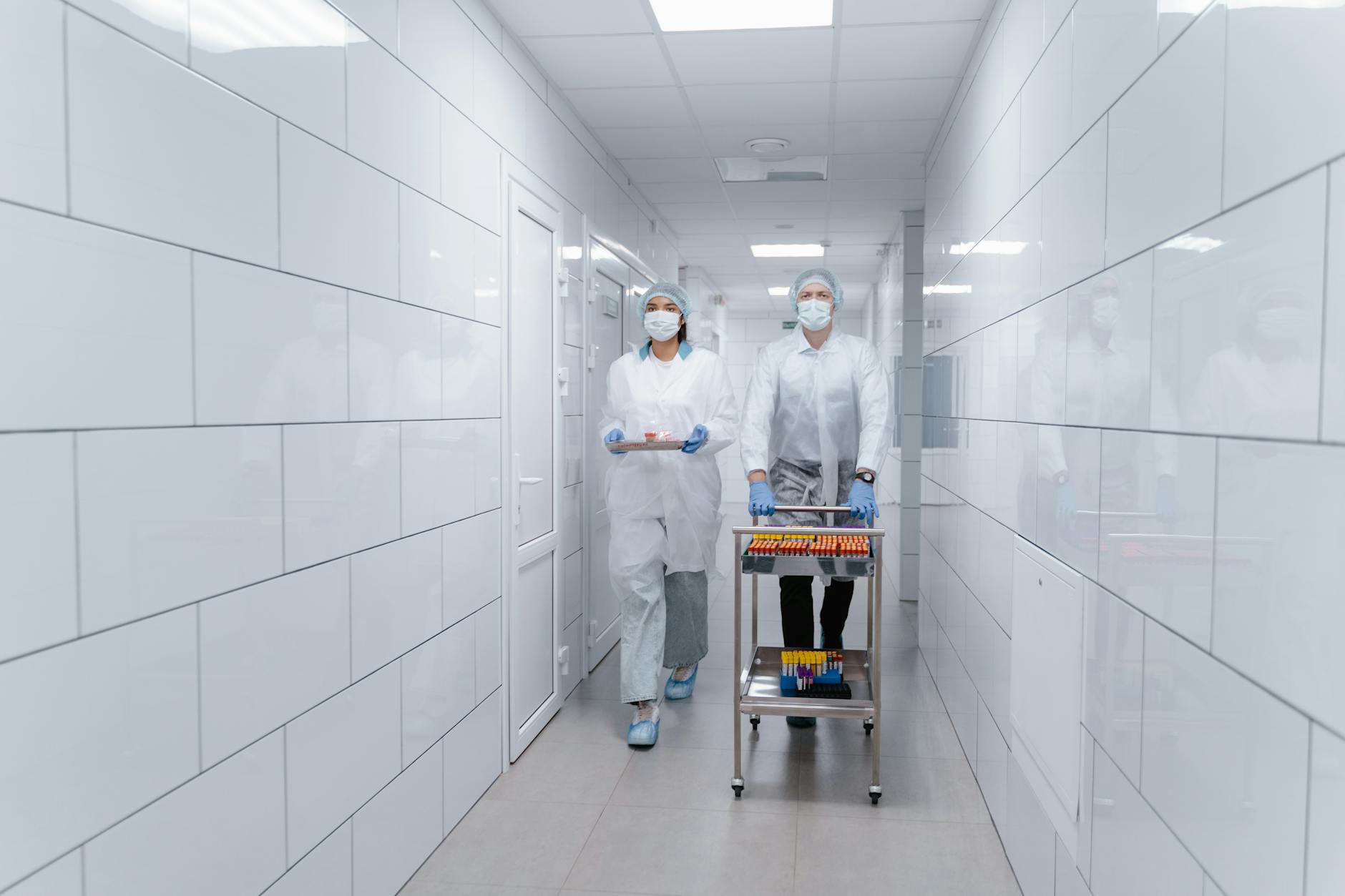 https://www.pexels.com/photo/people-walking-at-the-hallway-while-carrying-medical-supplies-9574413/